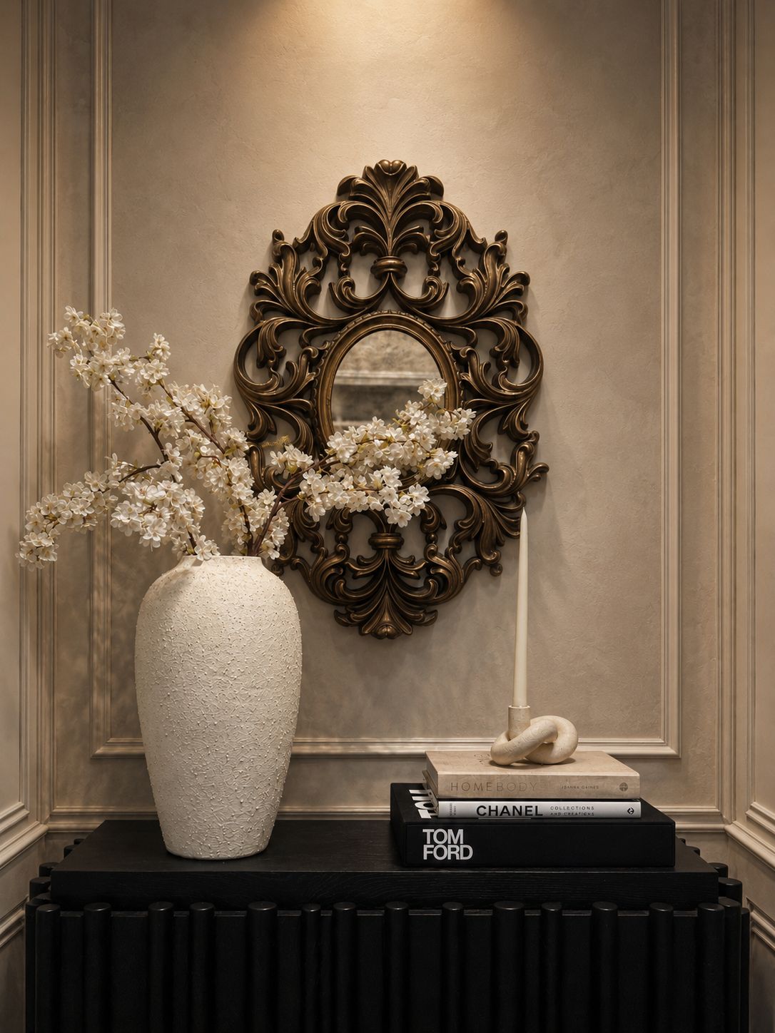 Styled console with ornate mirror, vase, and design books