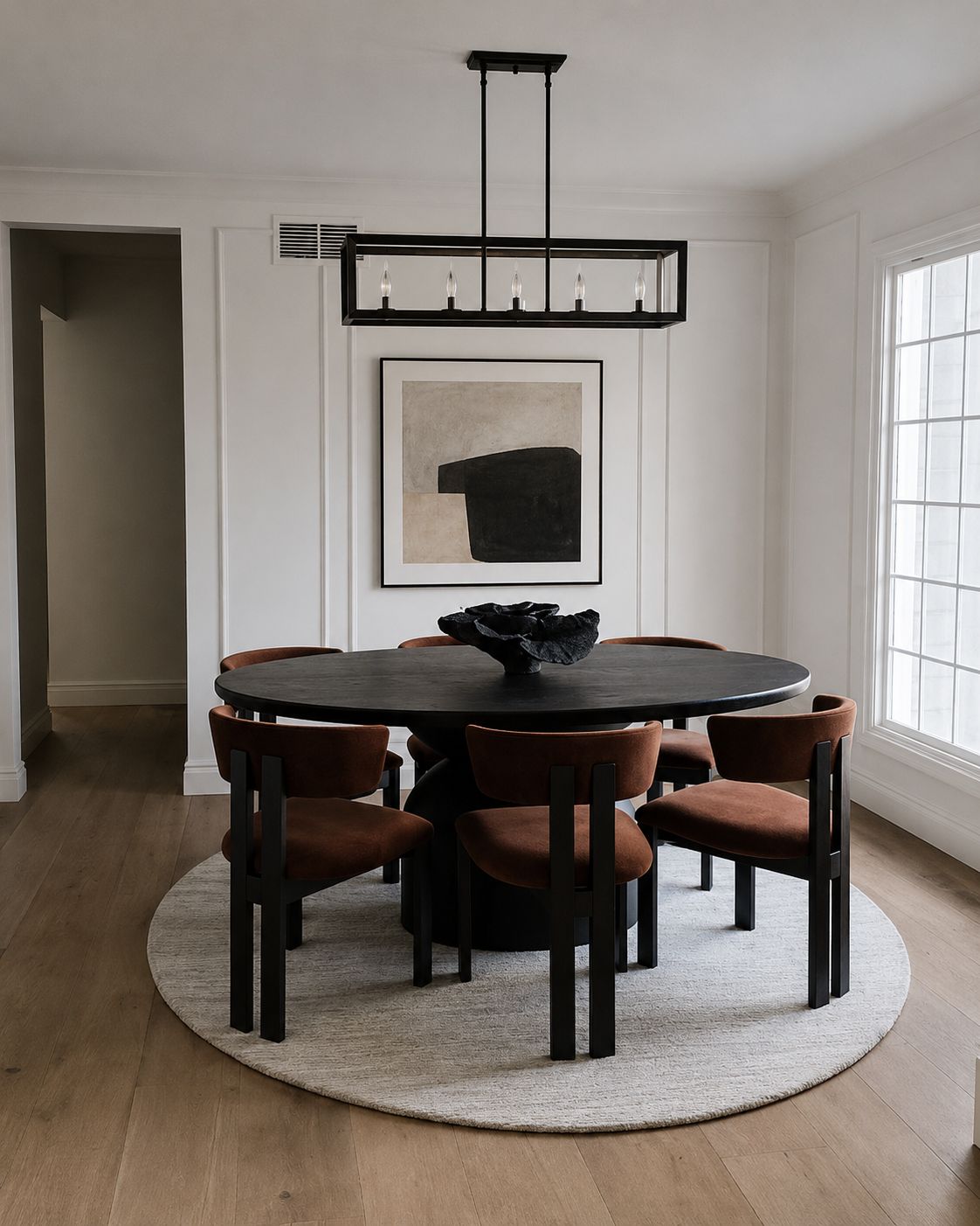 Round black dining table with rust upholstered chairs