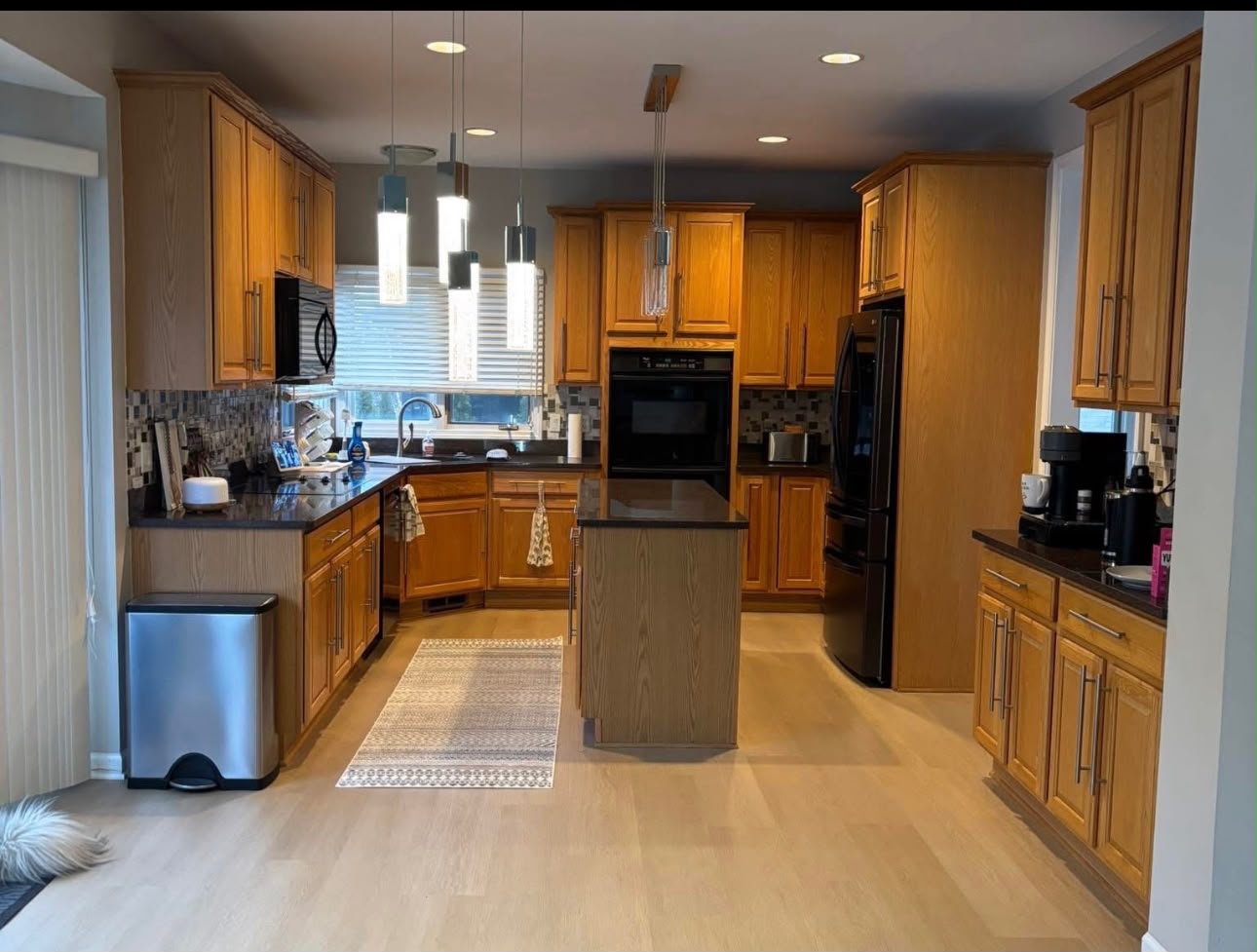 Kitchen before: honey oak cabinets, dark granite counters, and mosaic backsplash
